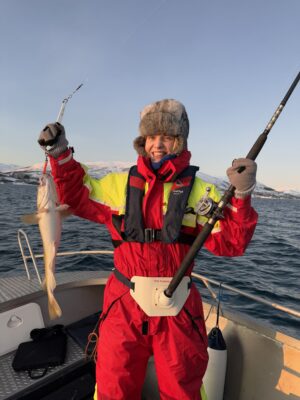 Happy guest holding a catch on a Private fishing tour Tromsø