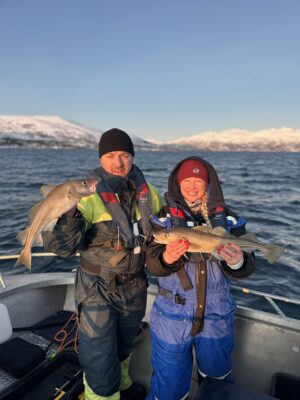 Happy guest holding fish during fishing tour Tromsø