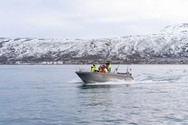 Guests on a private Arctic boat tour cruising near Tromsø with snow-covered hills in the background