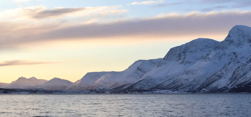 Golden winter sunset over Arctic fjord and snowy peaks near Tromsø