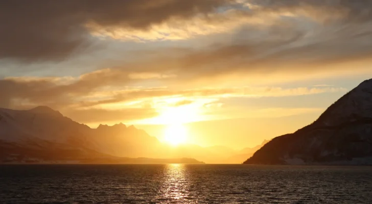 Golden Arctic sunset over fjord and snowy peaks near Tromsø in winter
