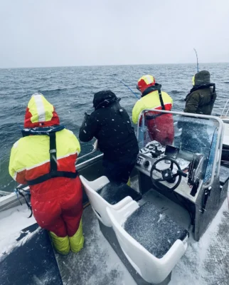 Three men on a fishing tour during a snowy weather near Tromsø