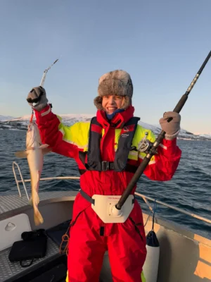 Smiling guest holding a cod after successful winter fishing on a private Arctic tour near Tromsø