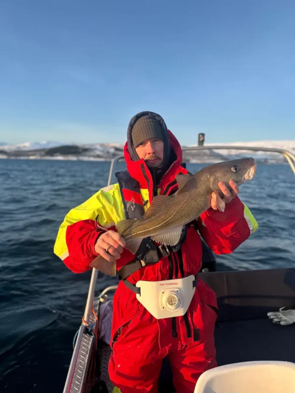 A man holding an Arctic cod caught on a private fishing tour in Tromsø