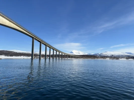 Kvaløya bridge stretching over a calm Arctic sea with mountains in the background