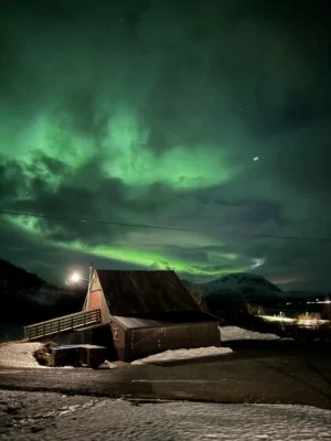 Peaceful cloudy night illuminated by magical Northern lights near Lyngen