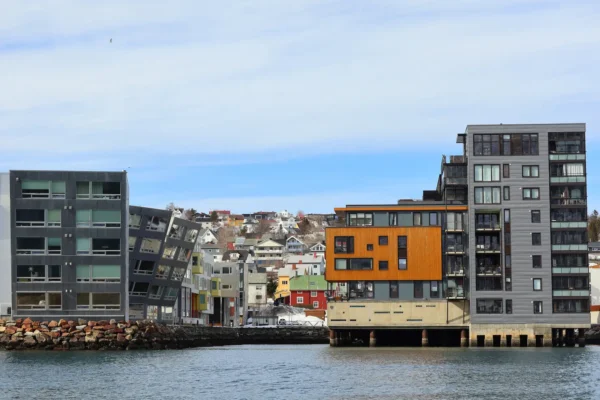 Contemporary waterfront buildings in Tromsø with hillside homes and colorful facades in the background