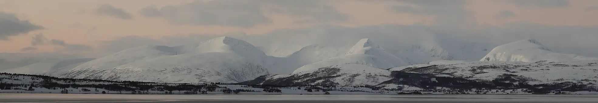 Panoramic view of cloudy winter skies over snowy mountains and fjord landscapes near Tromsø