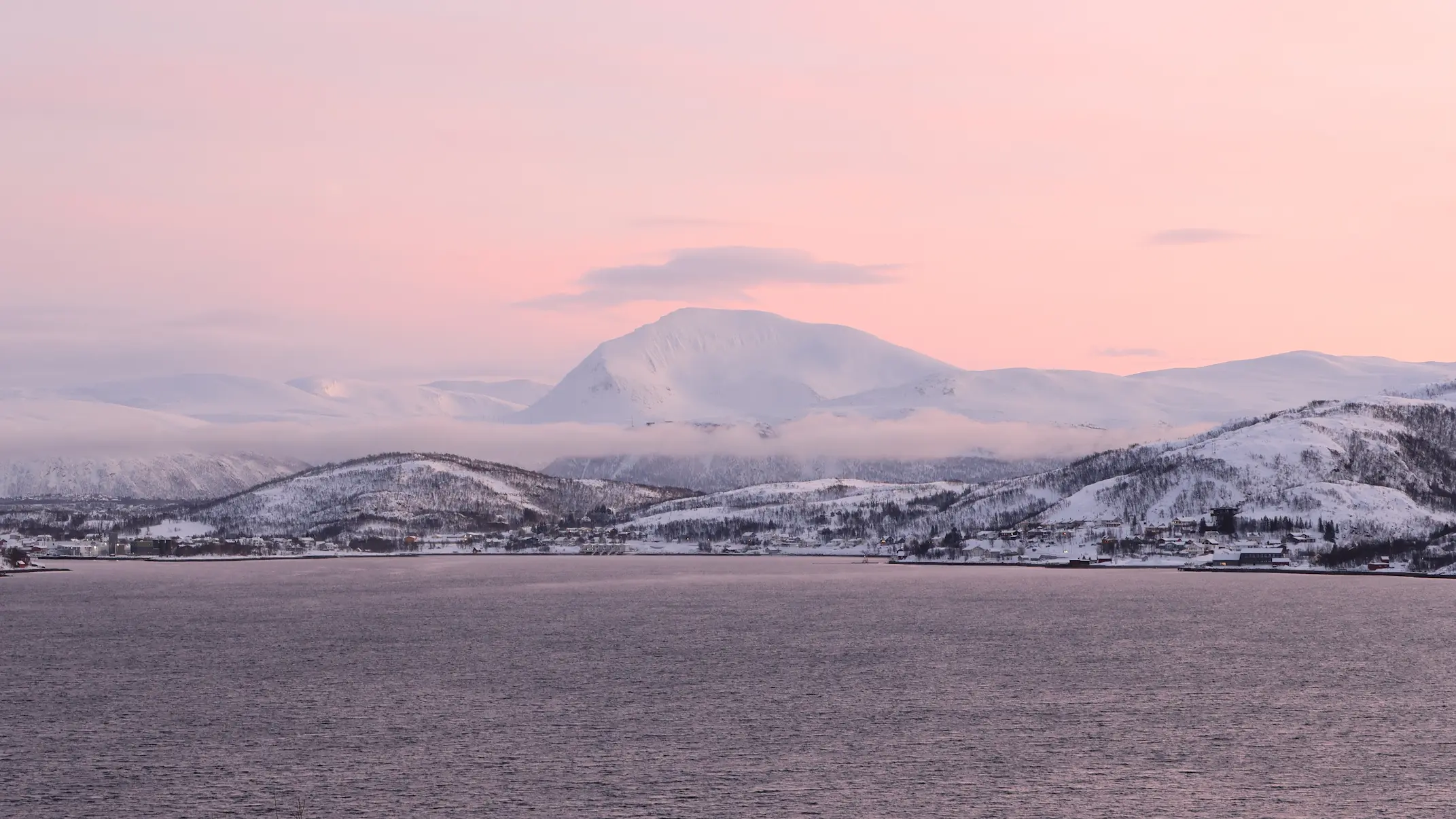 Pink winter sky above snowy Tromsdalstinden mountain and fjord landscape near Tromsø
