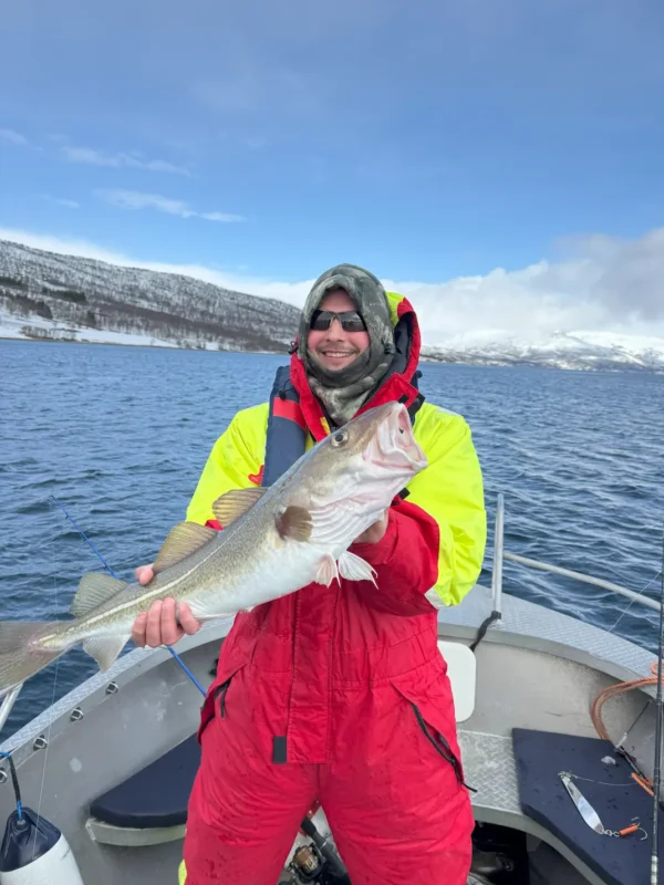Big fish and smile during a fishing trip on a boat with Arctic scenery in the background