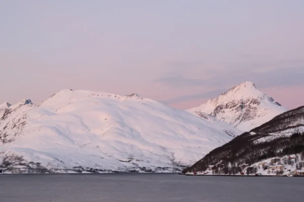 Snow-covered peaks glowing in soft pink light near Tromsø, Northern Norway