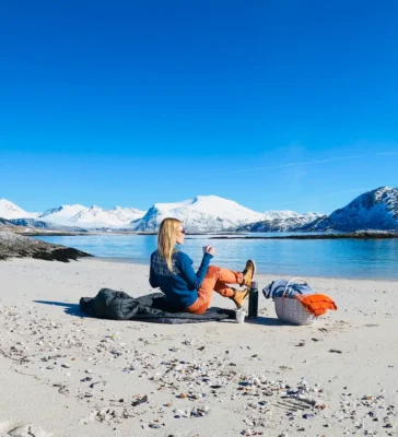 Guest enjoying a cup of tea on white sandy beach near Sommarøy