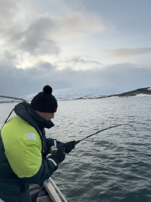 Man reeling in a fish during a winter private fishing tour in Tromsø, Norway