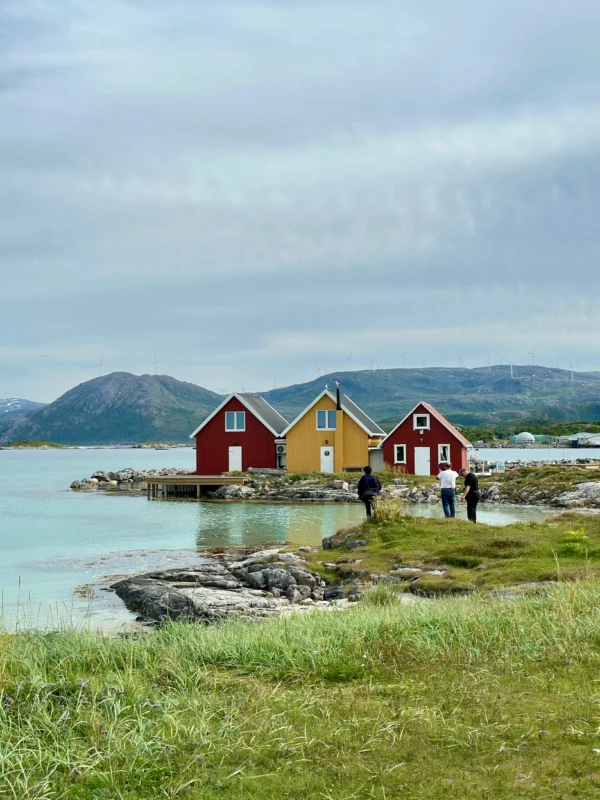 Colorful red and yellow cabins by the fjord with people exploring near Sommarøy, Tromsø, Norway.