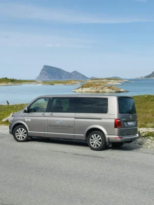 Tromsø Explorer tour van parked with a view of mountain and turquoise waters in Sommarøy, Norway.