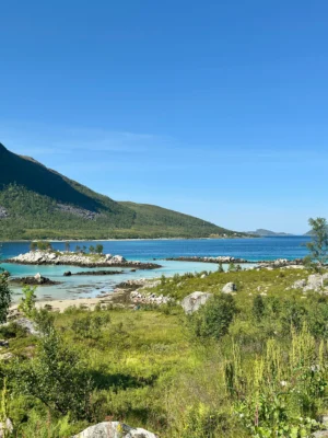 Beautiful turquoise bay surrounded by green hills and mountains near Sommarøy, Tromsø, Norway.