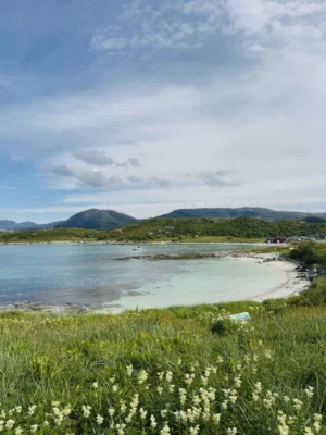White-sand beach with turquoise water and mountains in the background near Sommarøy, Tromsø, Norway.