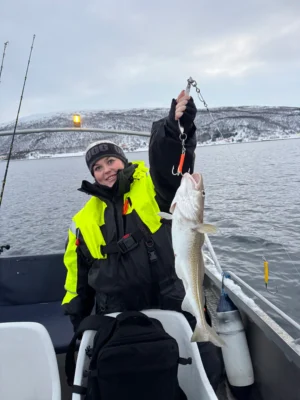 Guest holding a cod on board during a private fishing tour in Tromsø