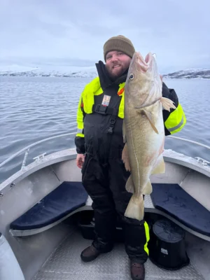 Guest holding a cod during a private fishing tour in Tromsø