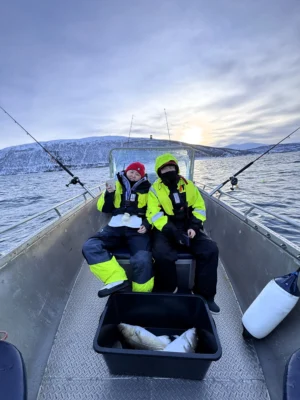 Guests sitting on a boat during a private fishing tour in Tromsø with cod caught in the fjord