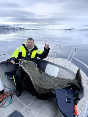 Guest holding a large halibut on a boat during a private fishing tour in Tromsø fjords