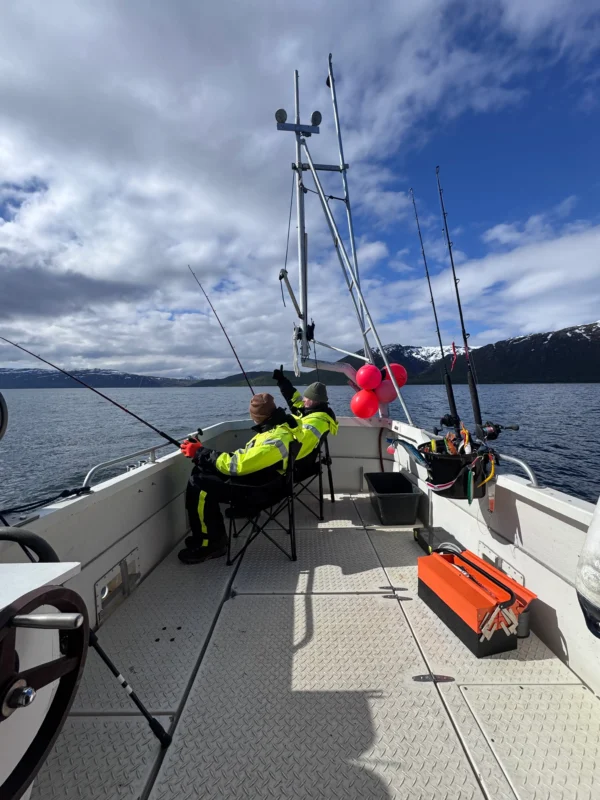 Guests relaxing and fishing on private fishing tour Tromsø aboard cabin boat in Arctic fjord