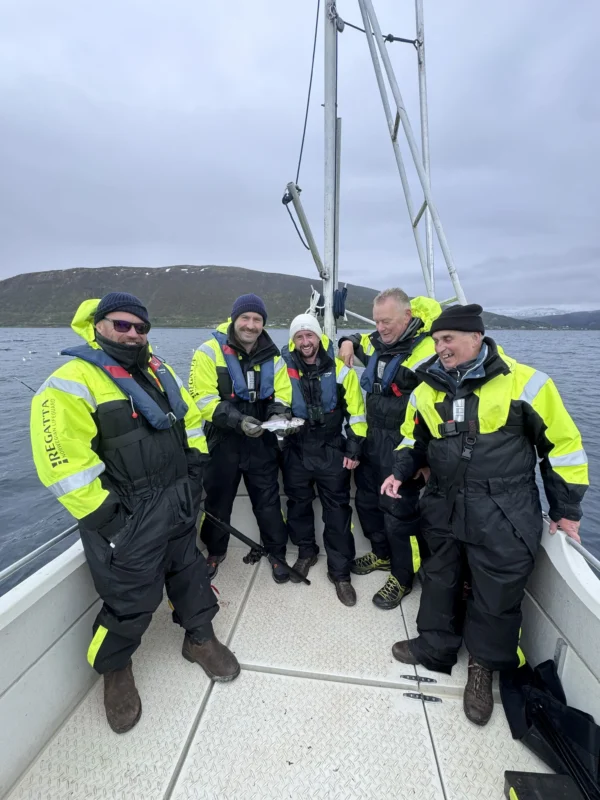 Group of guests enjoying private fishing tour Tromsø aboard cabin boat on Arctic fjord
